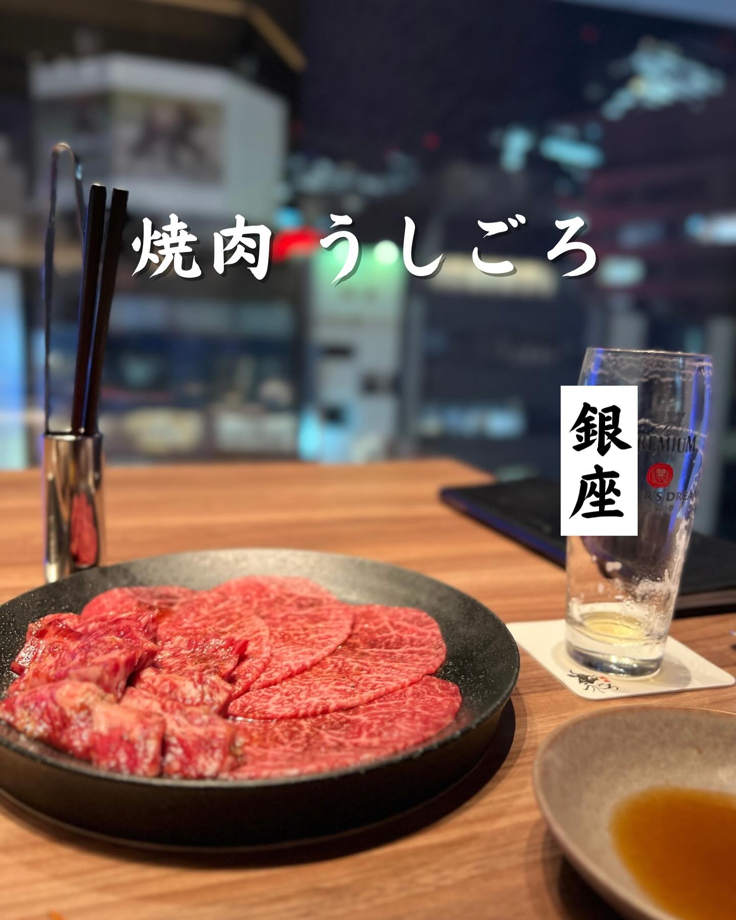 窓際のテーブルに並ぶ牛肉の皿と店舗名入りの表紙